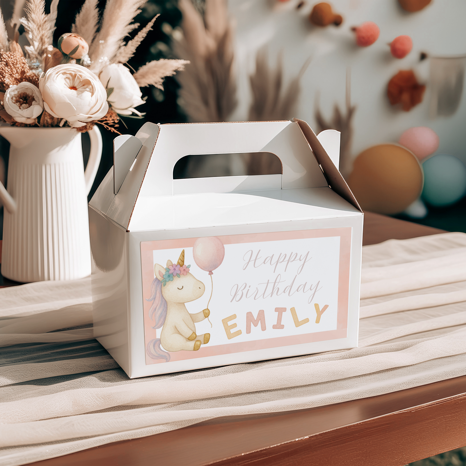Gift box with 'Happy Birthday' label on a table with flowers and balloons in the background