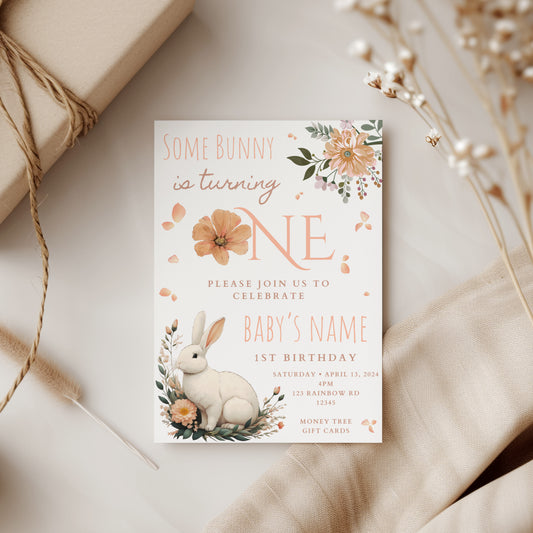 Invitation card for a first birthday party with a bunny and floral design on a neutral background.