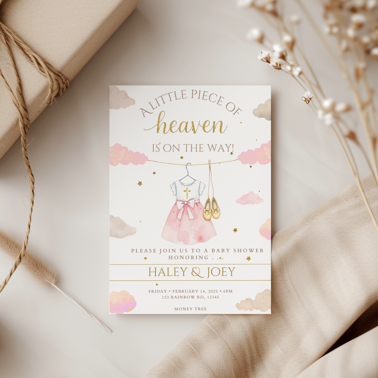 Baby shower invitation with pink dress and gold accents on a neutral background