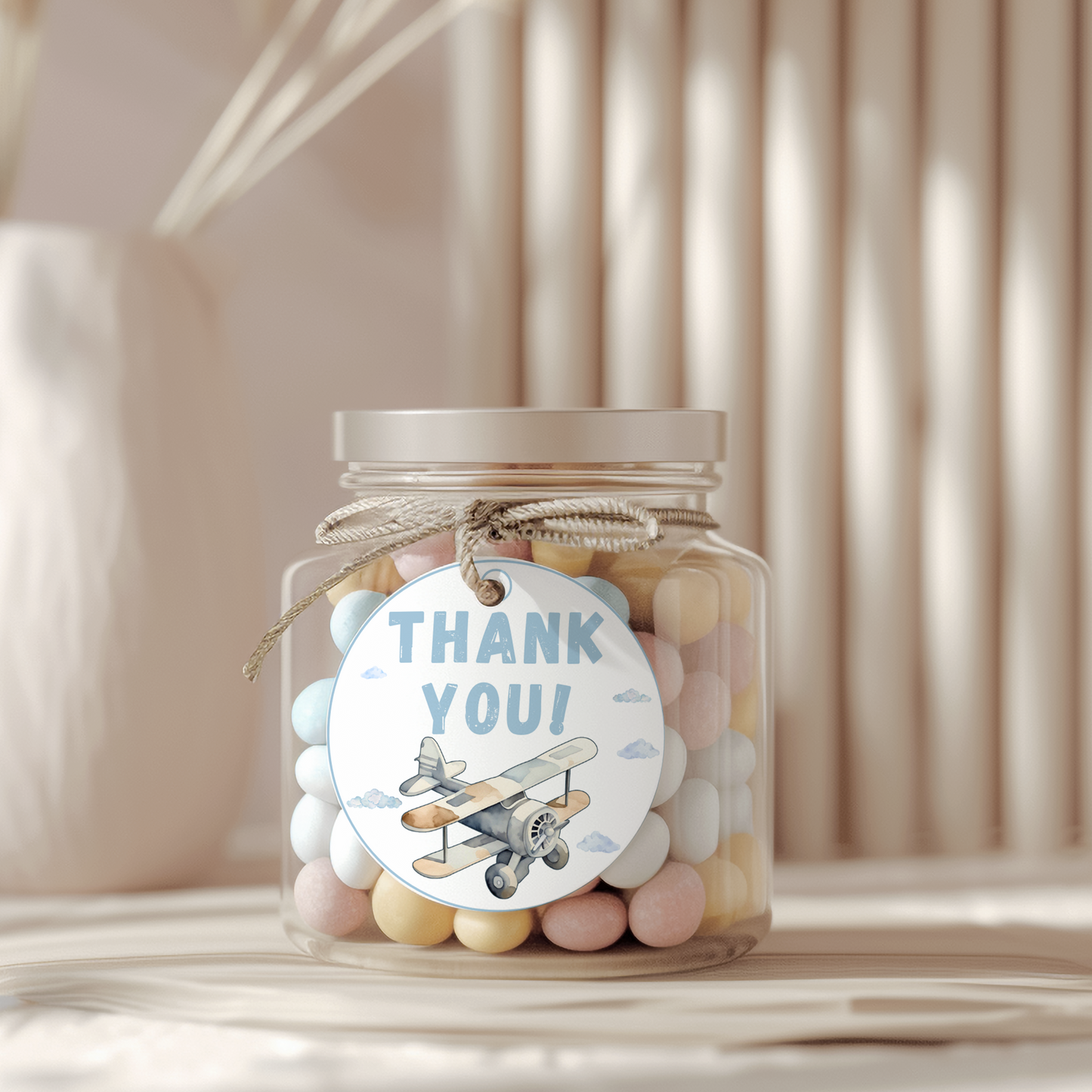 Jar of colorful candies with a 'Thank You' tag featuring an airplane illustration on a neutral background.