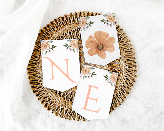 Three floral cards with 'ONE' on a woven tray for high chair