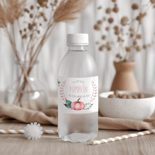 Clear water bottle with a decorative label featuring pumpkins and text, set against a blurred indoor background.
