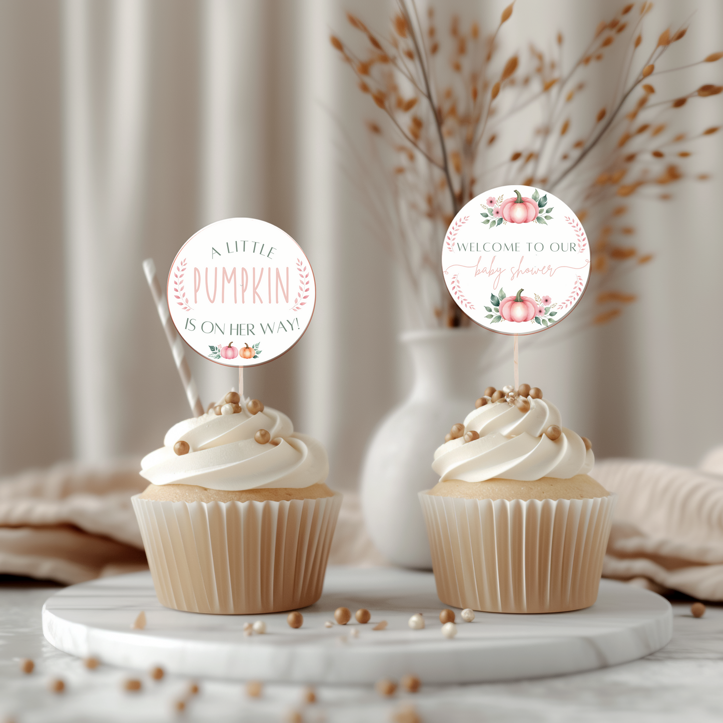 Two cupcakes with decorative toppers on a marble surface with a neutral background