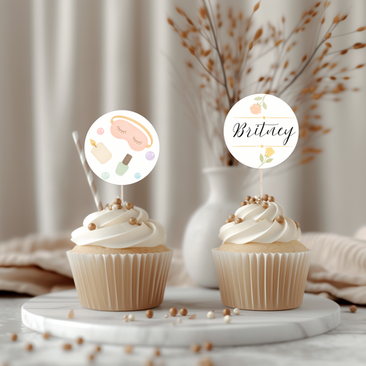 Two cupcakes with decorative toppers on a marble surface with a neutral background