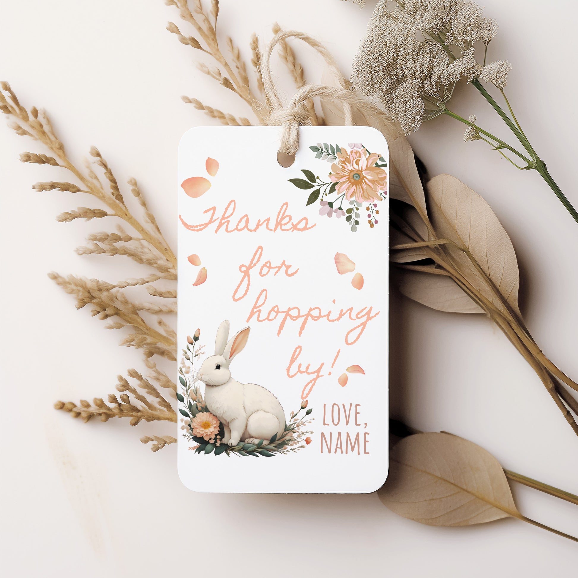 Gift tag with a bunny and floral design on a white background with dried plants.
