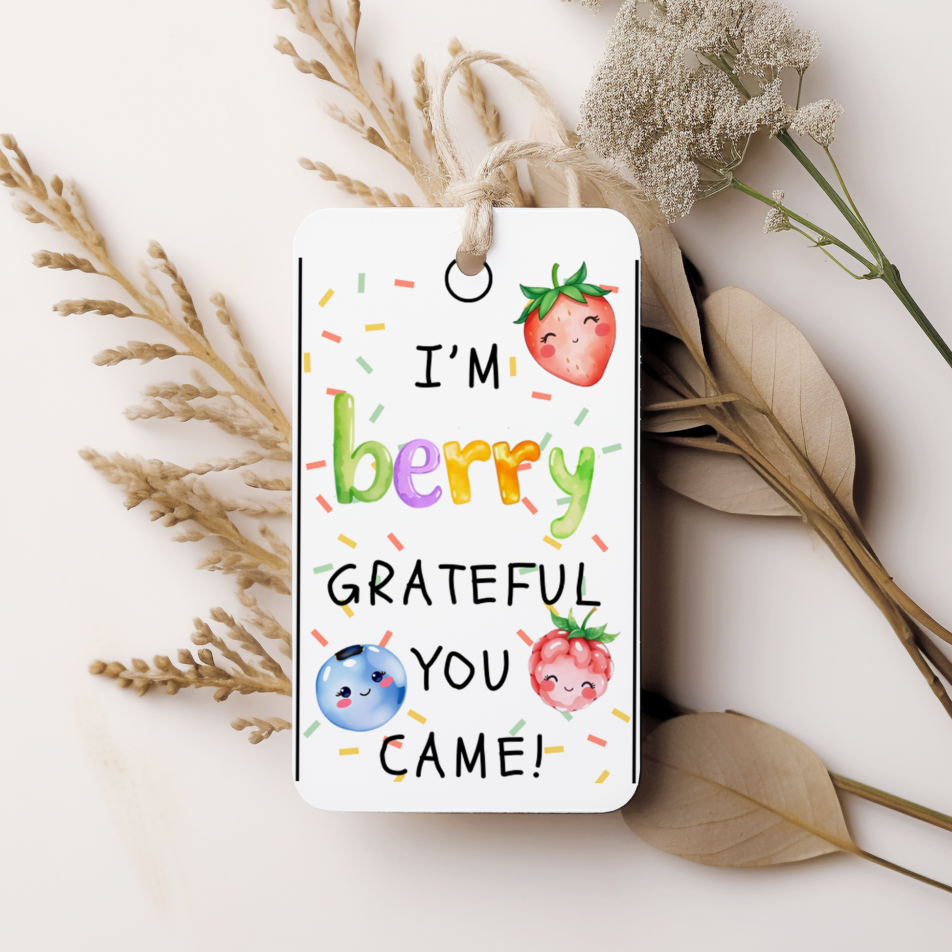 Gift tag with colorful text and fruit illustrations on a white background with dried plants.