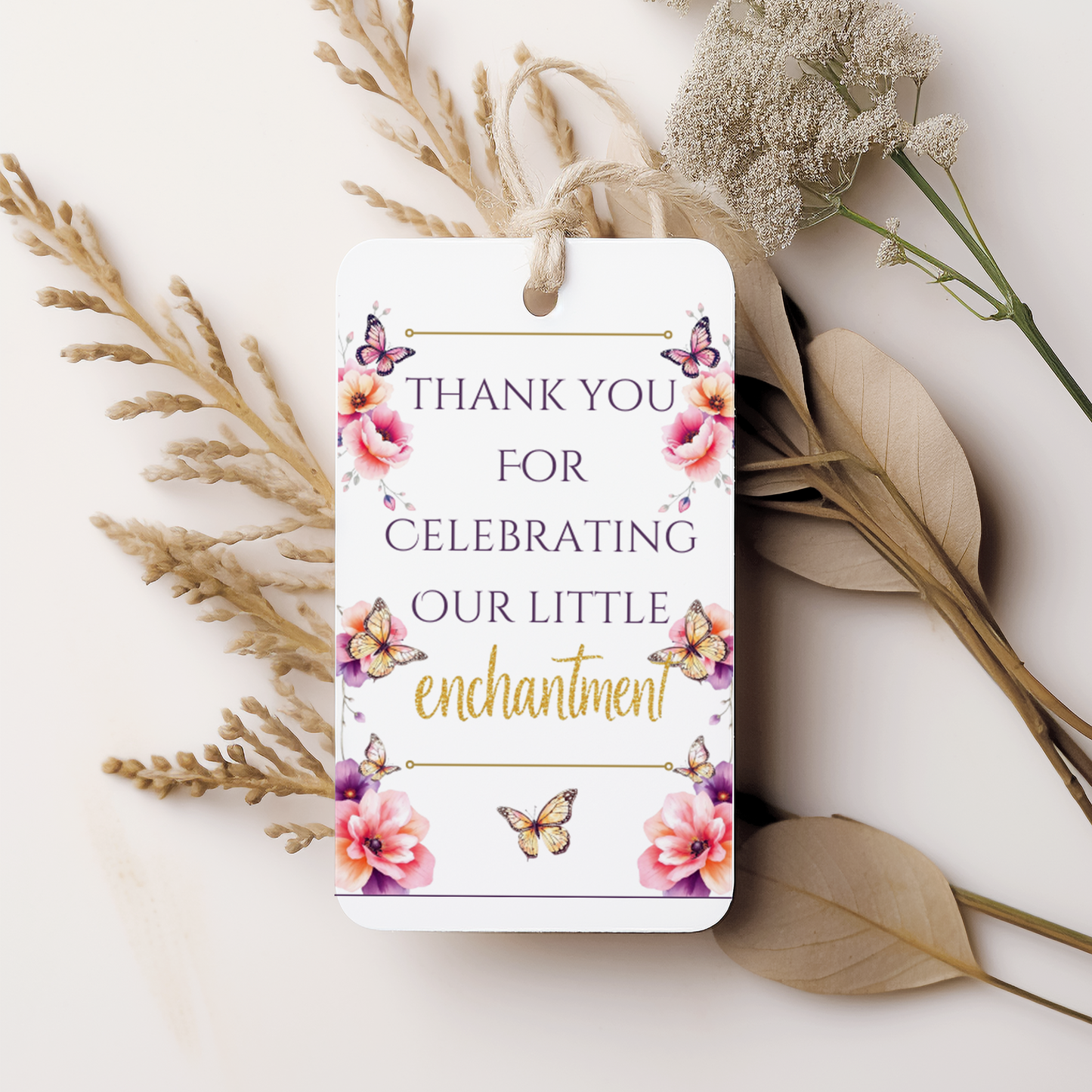 Gift tag with floral design and text 'Thank you for celebrating our little enchantment' on a white background with dried flowers.