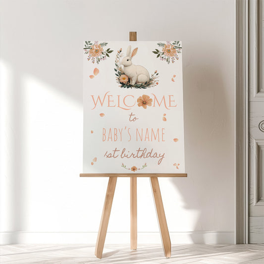 Decorative sign with a rabbit illustration on an easel against a white wall.