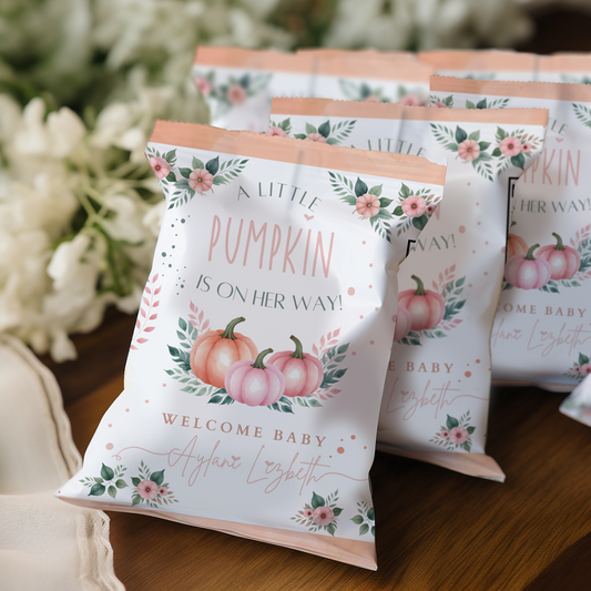Pumpkin-themed baby shower favor bags with floral designs on a wooden surface.