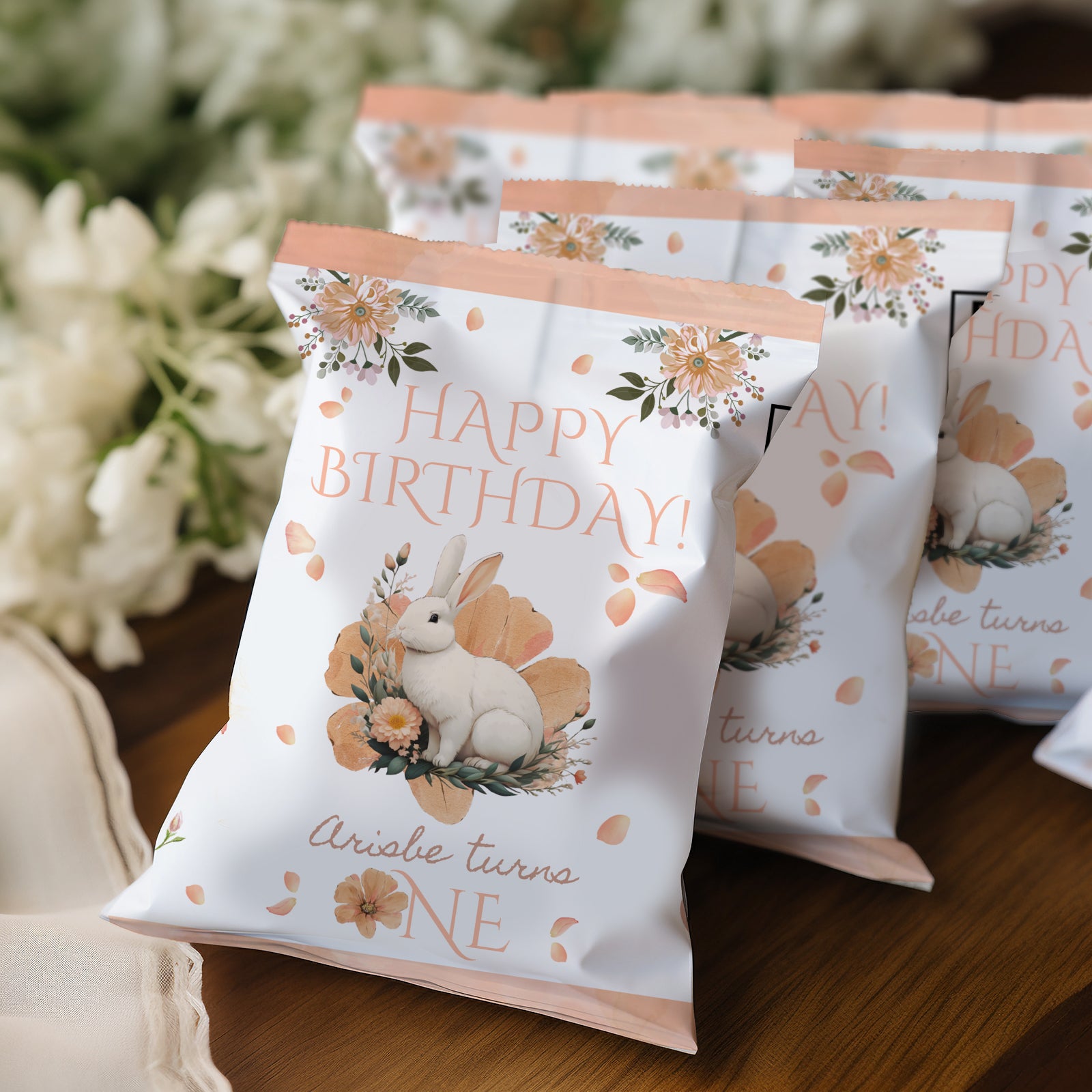 Birthday-themed treat bags with a rabbit illustration on a wooden surface.