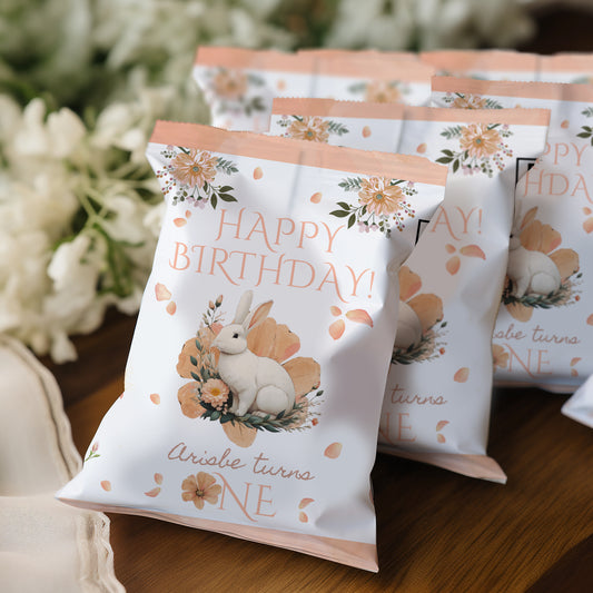 Birthday-themed treat bags with a rabbit illustration on a wooden surface.
