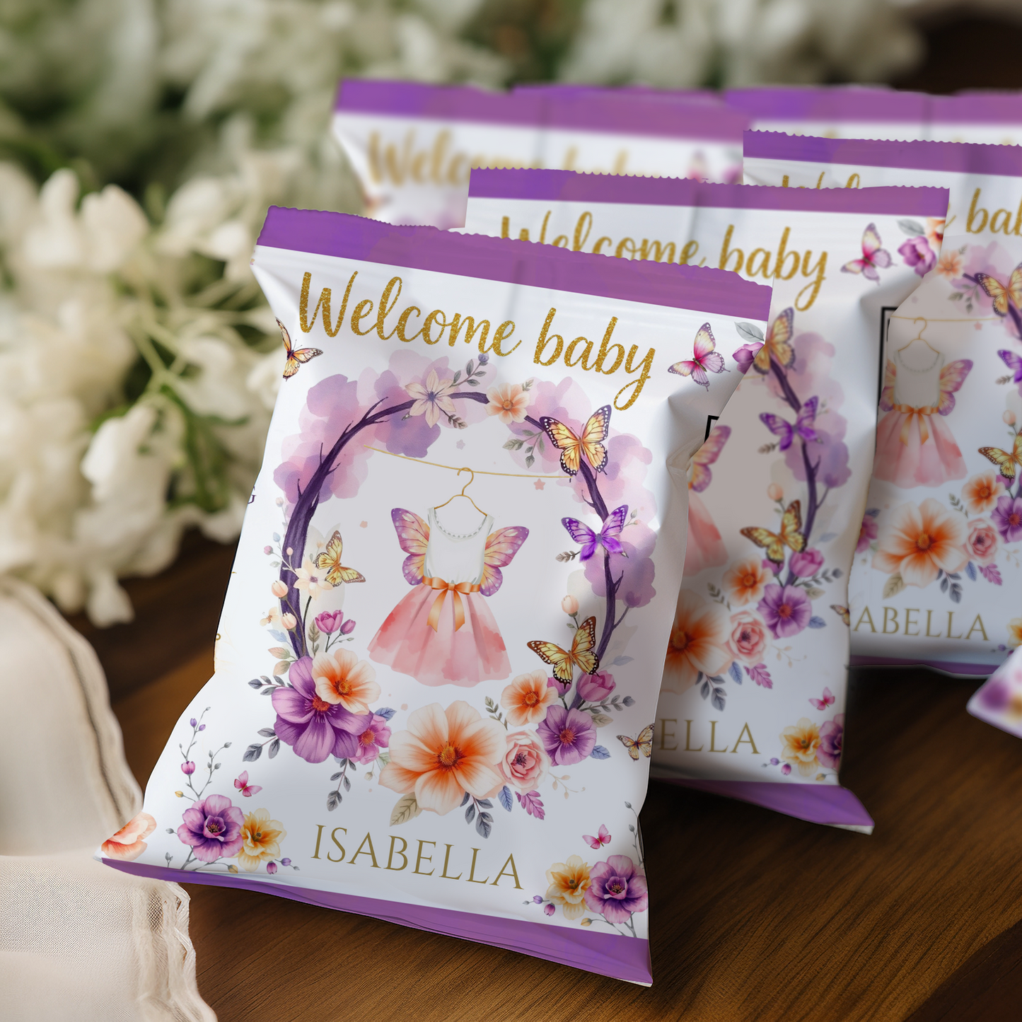 Packets with 'Welcome baby' and floral designs on a wooden surface with blurred flowers in the background