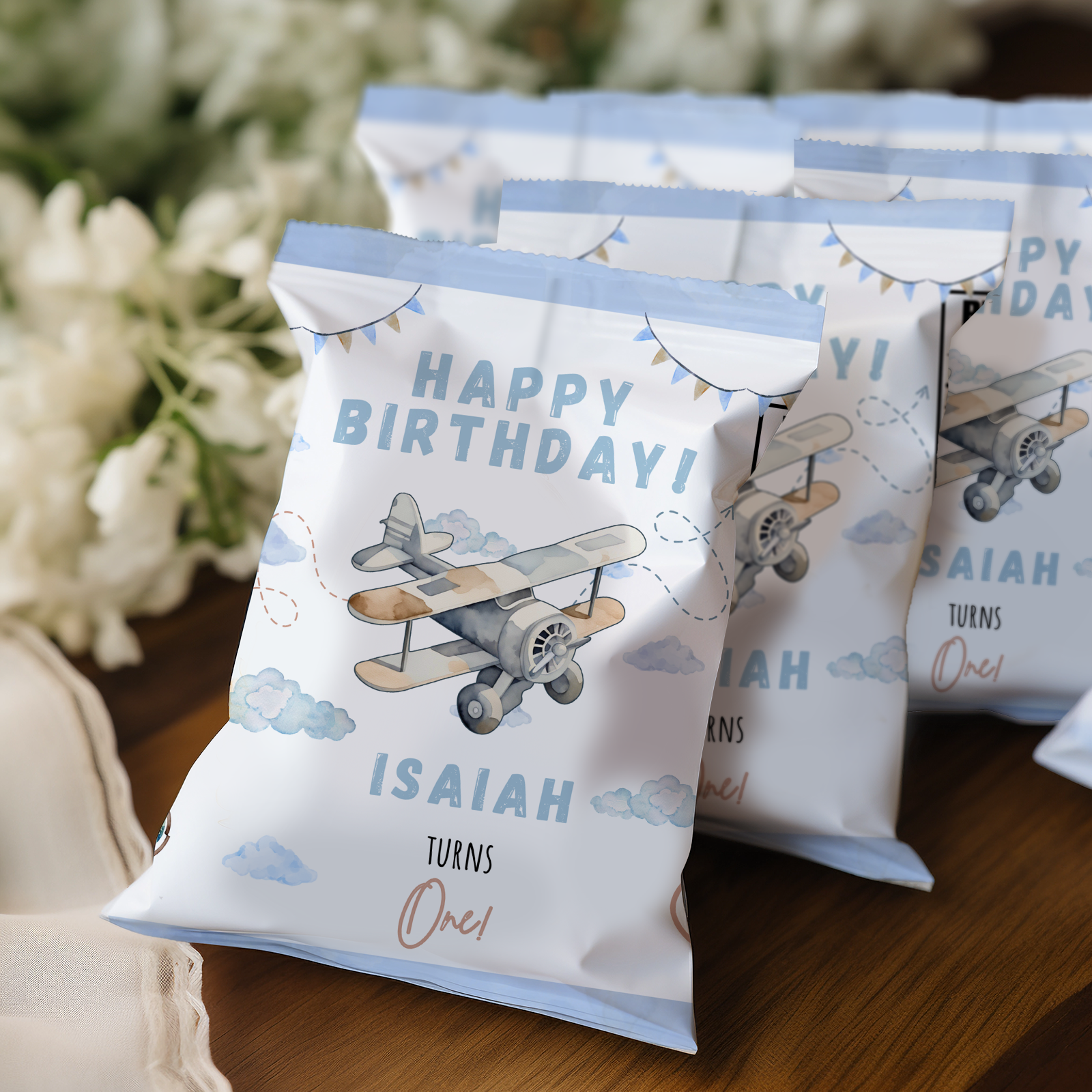 Personalized birthday party favor bags with airplane design on a wooden surface.