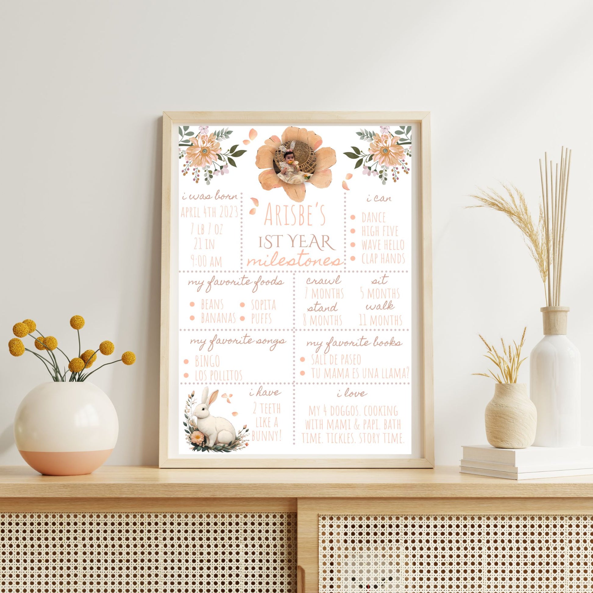 Framed milestone chart for a child's first year on a decorative shelf with vases.