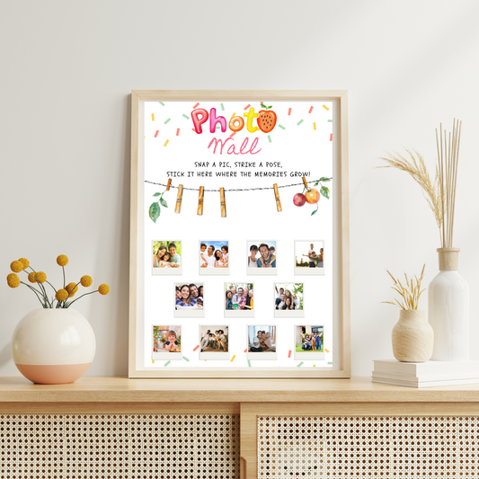 Framed 'Photo Wall' display with family photos on a wooden shelf.