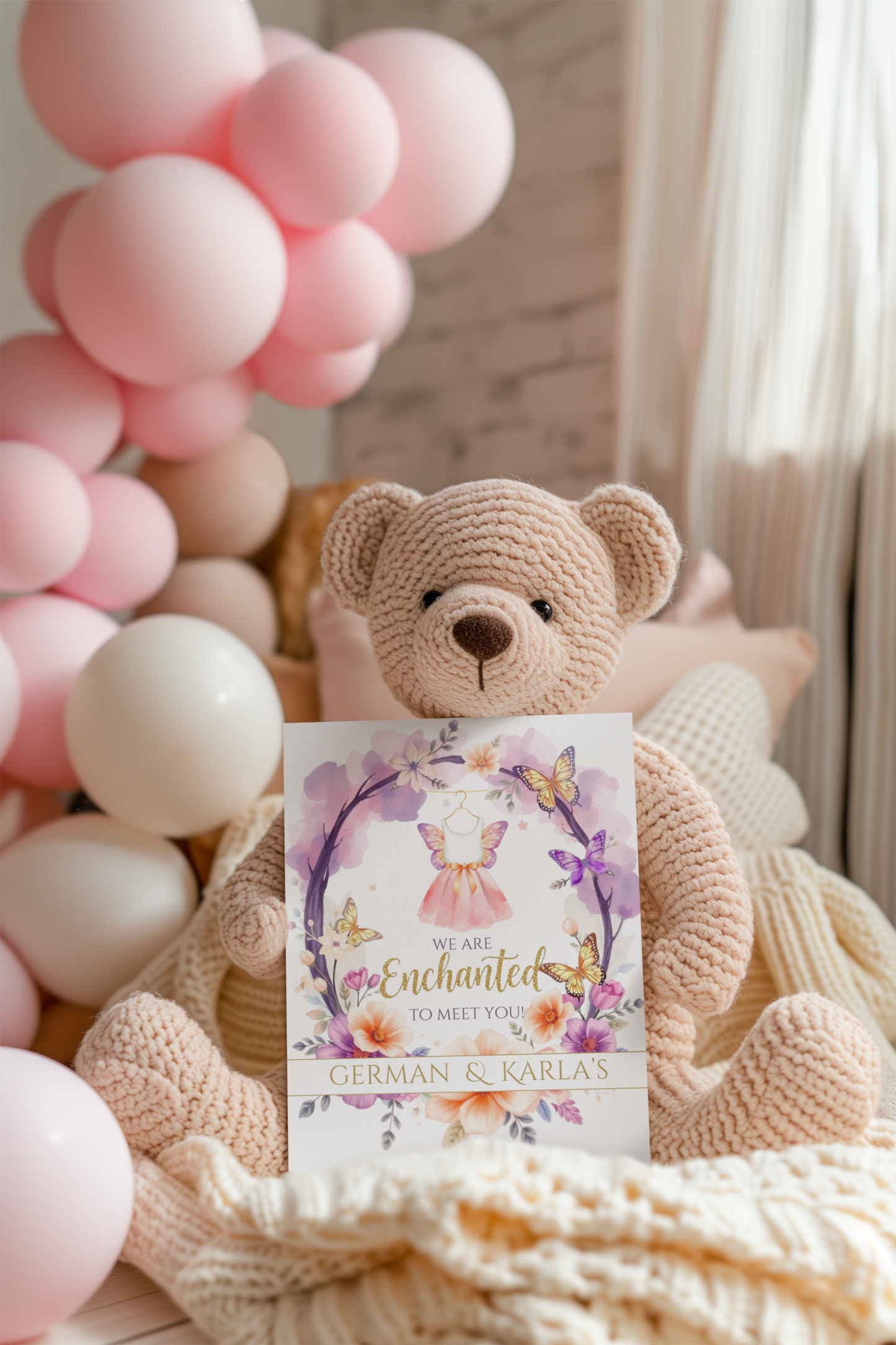 Teddy bear with a card surrounded by pink balloons and a blanket