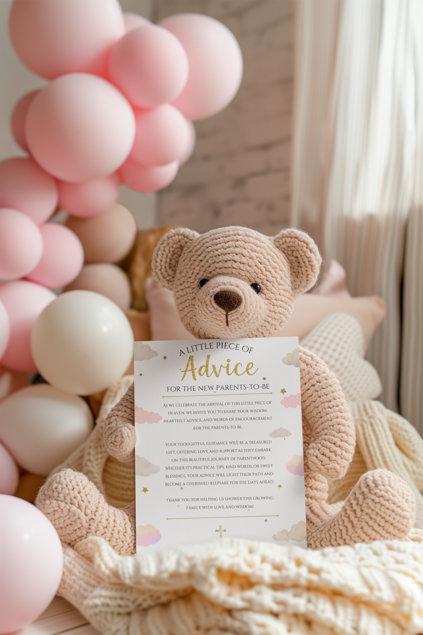 Knitted teddy bear with a piece of paper and pink balloons in the background