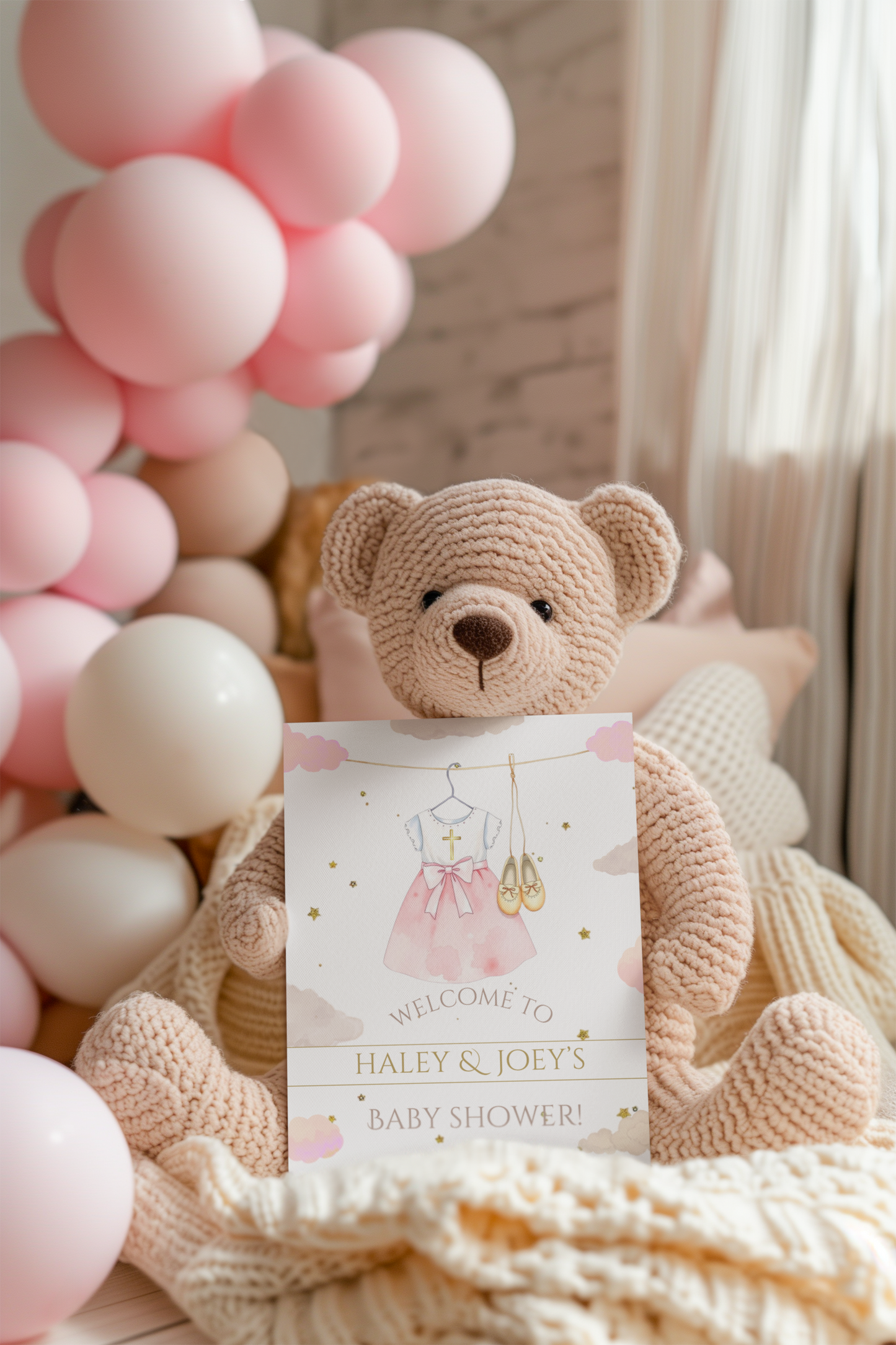 Teddy bear holding a baby shower invitation with pink balloons in the background