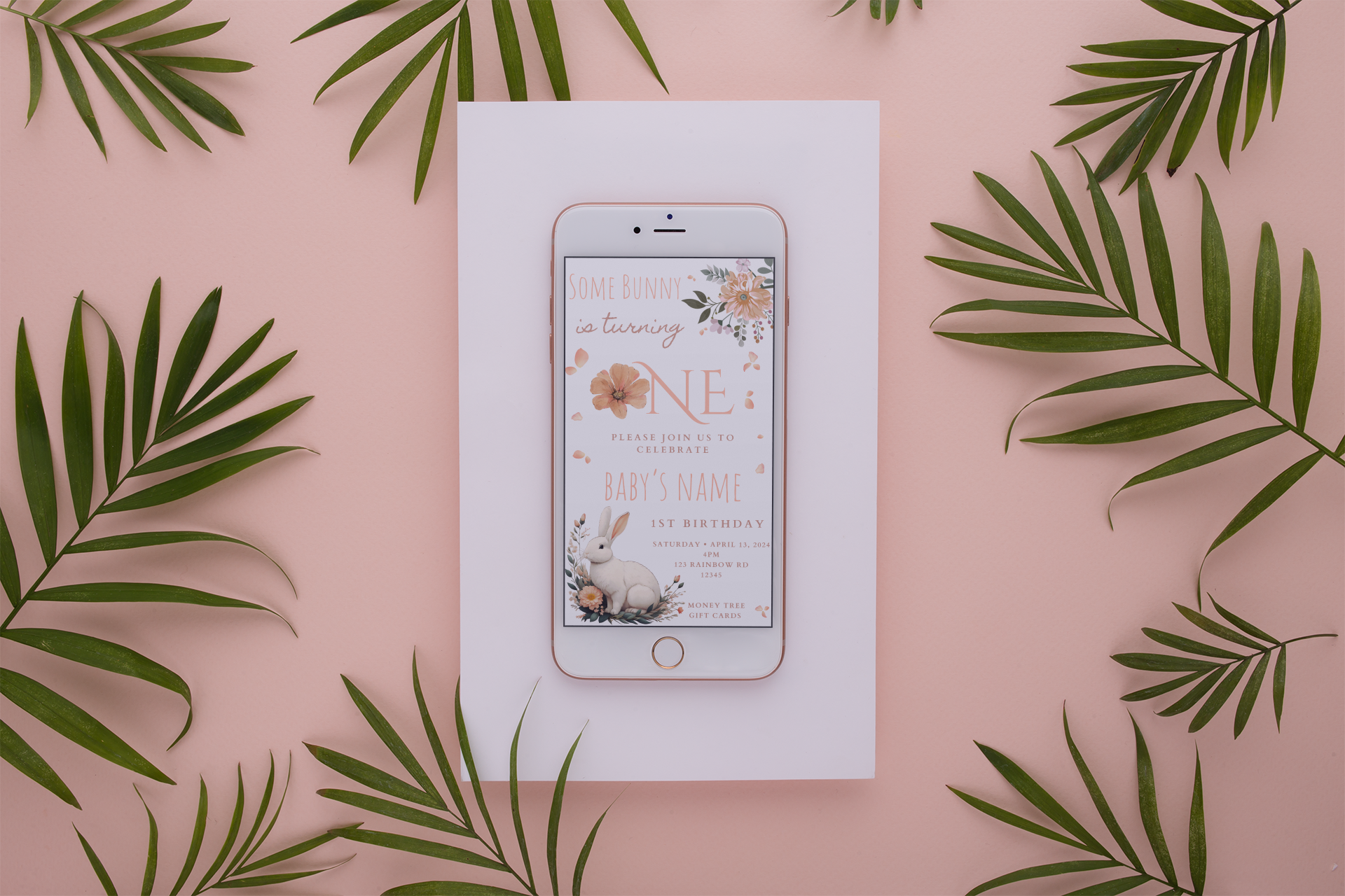 Phone displaying a baby shower invitation on a pink background with green leaves