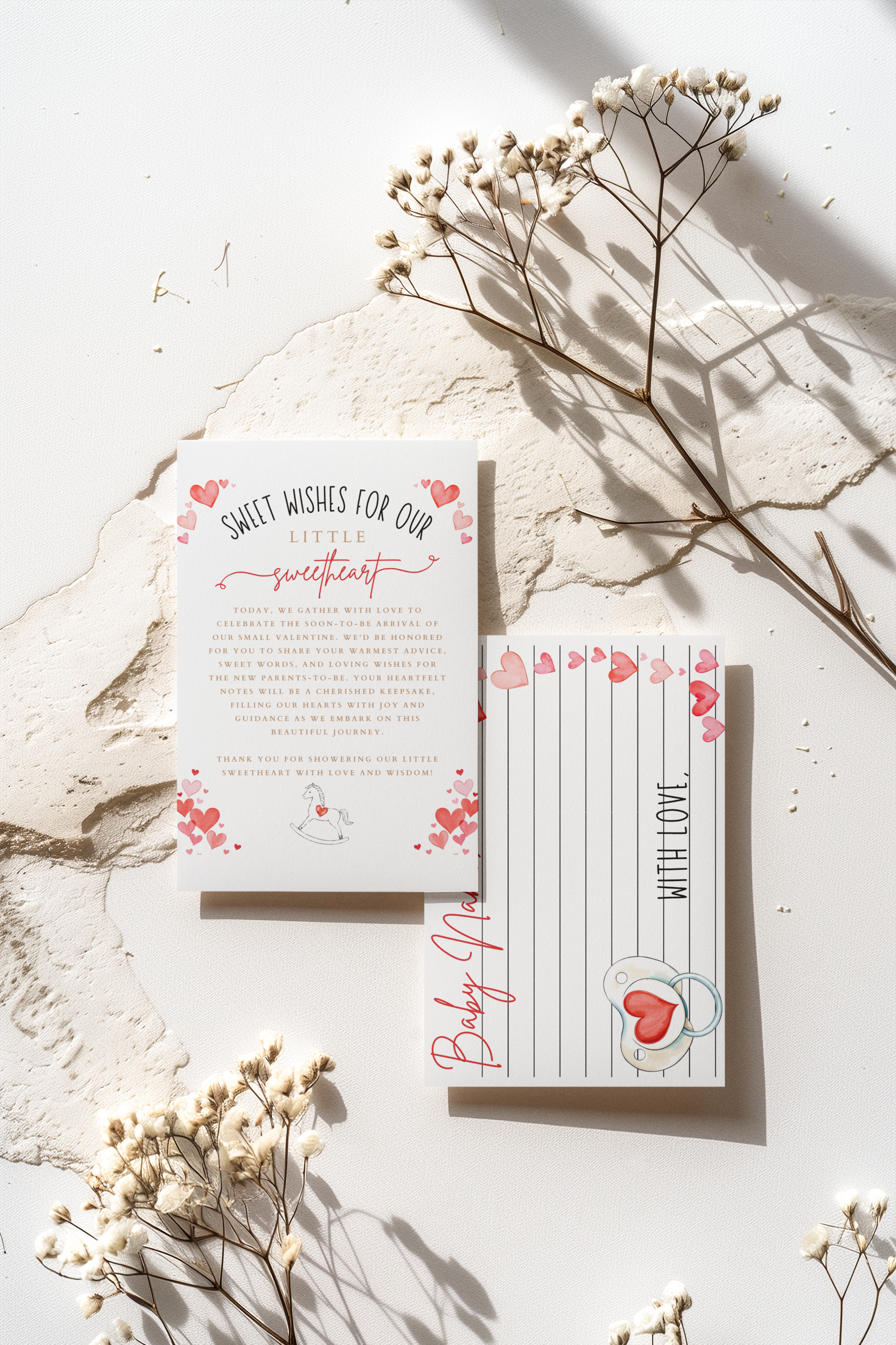 Baby shower invitations with floral design on a light surface with dried flowers.