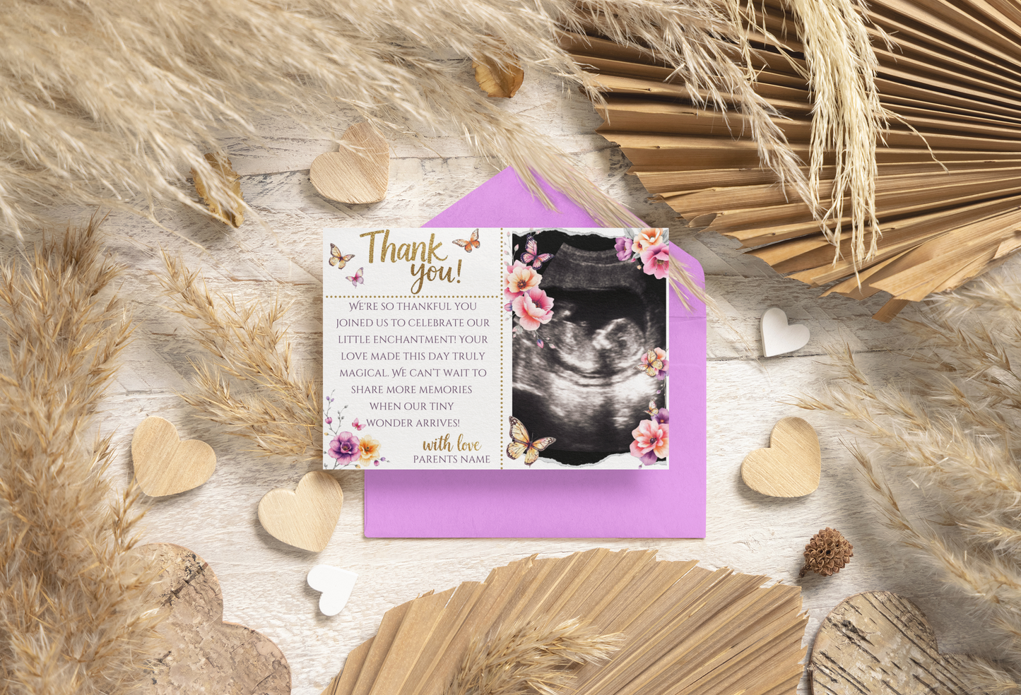 Greeting card with ultrasound photo and floral design on a textured surface with dried plants and hearts.